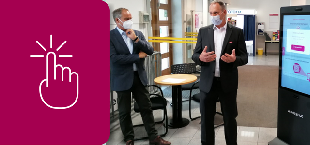 Oberbürgermeister Eckart Würzner steht zusammen mit einem Mitarbeiter der Firma Ameria vor dem berührungslosen Infopoint