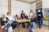 Oberbürgermeister Prof. Dr. Eckart Würzner und Sozialbürgermeisterin Stefanie Jansen (Mitte stehend) besuchten zum offiziellen Start am 30. Mai die Begegnungsstätte für ukrainische Geflüchtete in der ehemaligen Julius-Springer-Schule auf dem Schulcampus in der Südstadt. Natalia Jäger (3.v.l.) ist dort die verantwortliche Ansprechpartnerin. (Foto: Rothe) Foto mit Erwachsenen und Kindern am Tisch