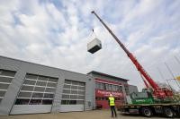 Kran hebt Notstromaggregat in die Luft.