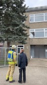 Feuerwehrmann schaut auf ein Haus, aus dem Rauch aus einem Fenster dringt