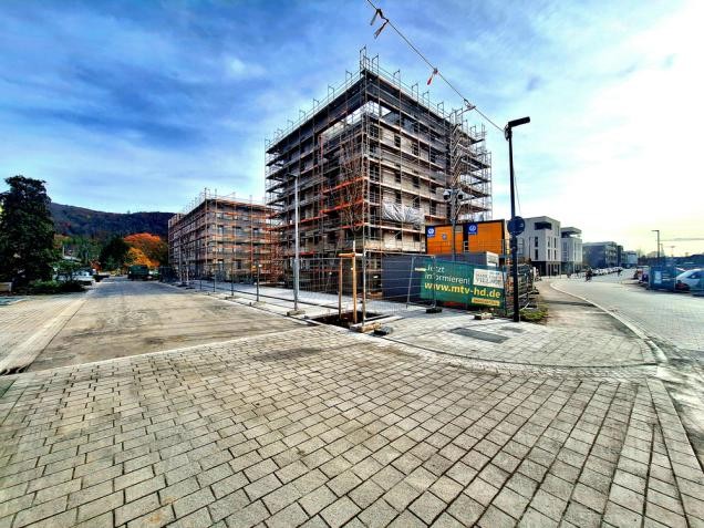 Neue Südstadt: Erhöhungen an den Kreuzungen tragen zur Verkehrsberuhigung und Sicherheit für alle Verkehrsteilnehmenden bei (Foto: Entwicklungsgesellschaft Campbell Barracks mbH) Zu sehen ist ein, mit einem Gerüst verkleideten, mehrstöckiges Gebäude.