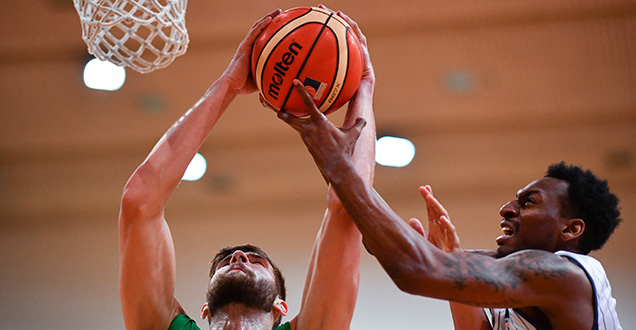 Zwei sich im Sprung befindende Männer; einer davon ist gerade im Begriff, einen Basketball in den Korb zu werfen (Photo: Anspach)