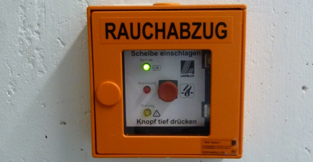 Der Taster zur Betätigung des Rauchabzuges steht symbolisch für die Forderungen die der Vorbeugende Brandschutz stellt, um Feuer möglichst zu vermeiden und einzudämmen.