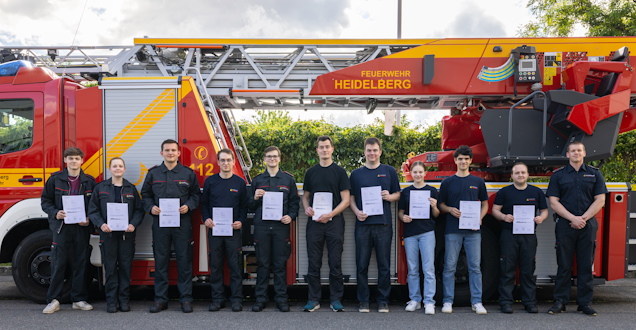 Die Lehrgangsteilnehmer zeigen stolz ihre Urkunde, im Hintergrund die Drehleiter der Berufsfeuerwehr Die Lehrgangsteilnehmer zeigen stolz ihre Urkunde, im Hintergrund die Drehleiter der Berufsfeuerwehr