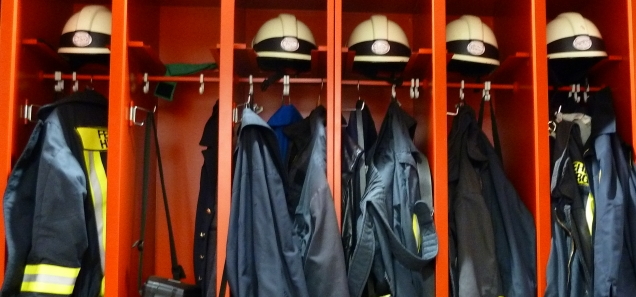 Dienstbetrieb Blick auf Spinde mit Feuerwehrhelmen und Einsatzjacken